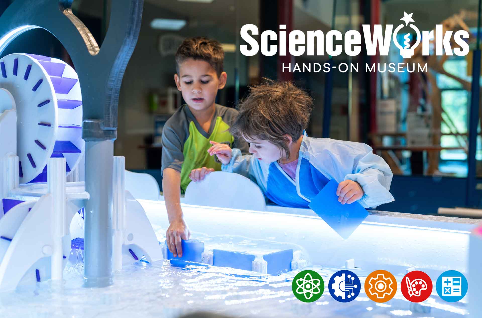Two children explore a hands-on water exhibit at ScienceWorks Hands-On Museum, pouring water and blocks at an interactive science table.