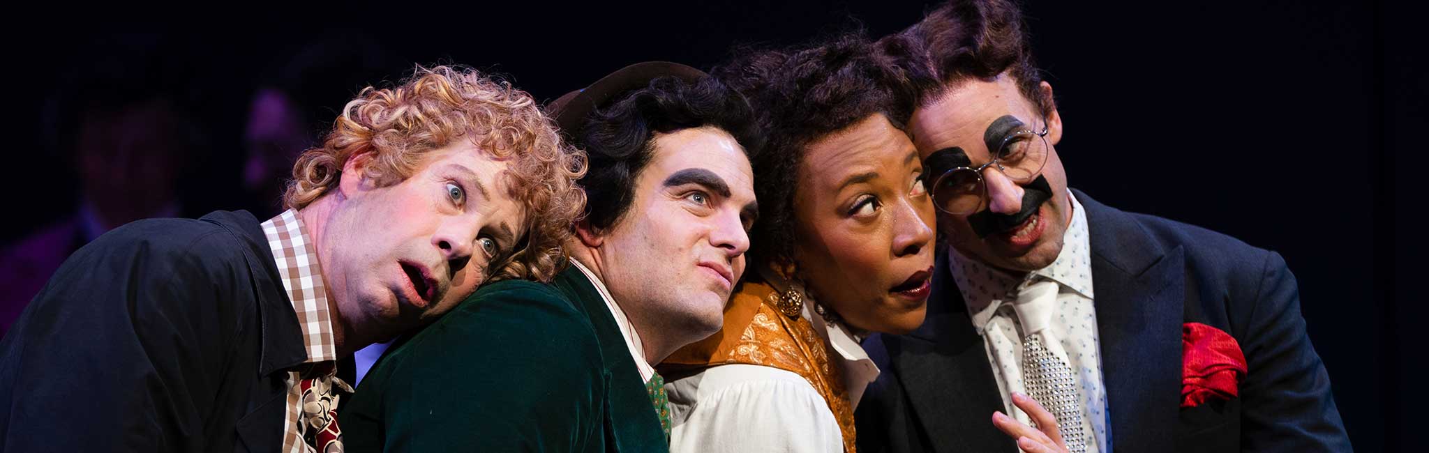 Four people with their heads on each other shoulders looking out into the distance.