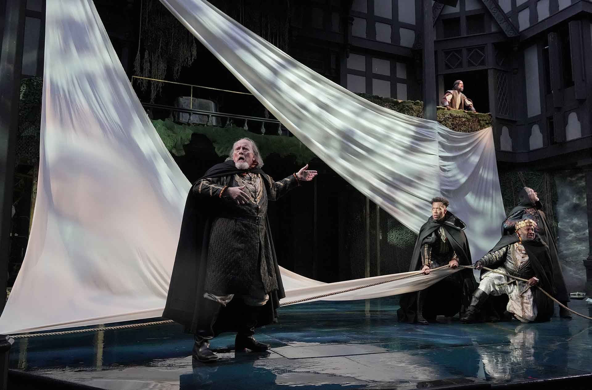 Ship scene with large white sails and worried men looking into the distance.