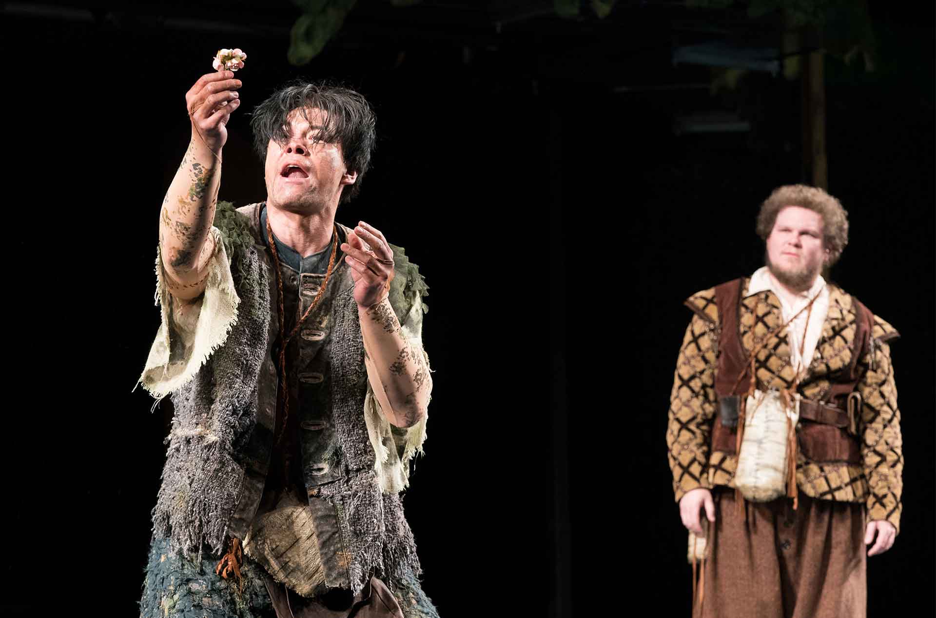 Man looking at an object in his hand, with another man watching behind him.