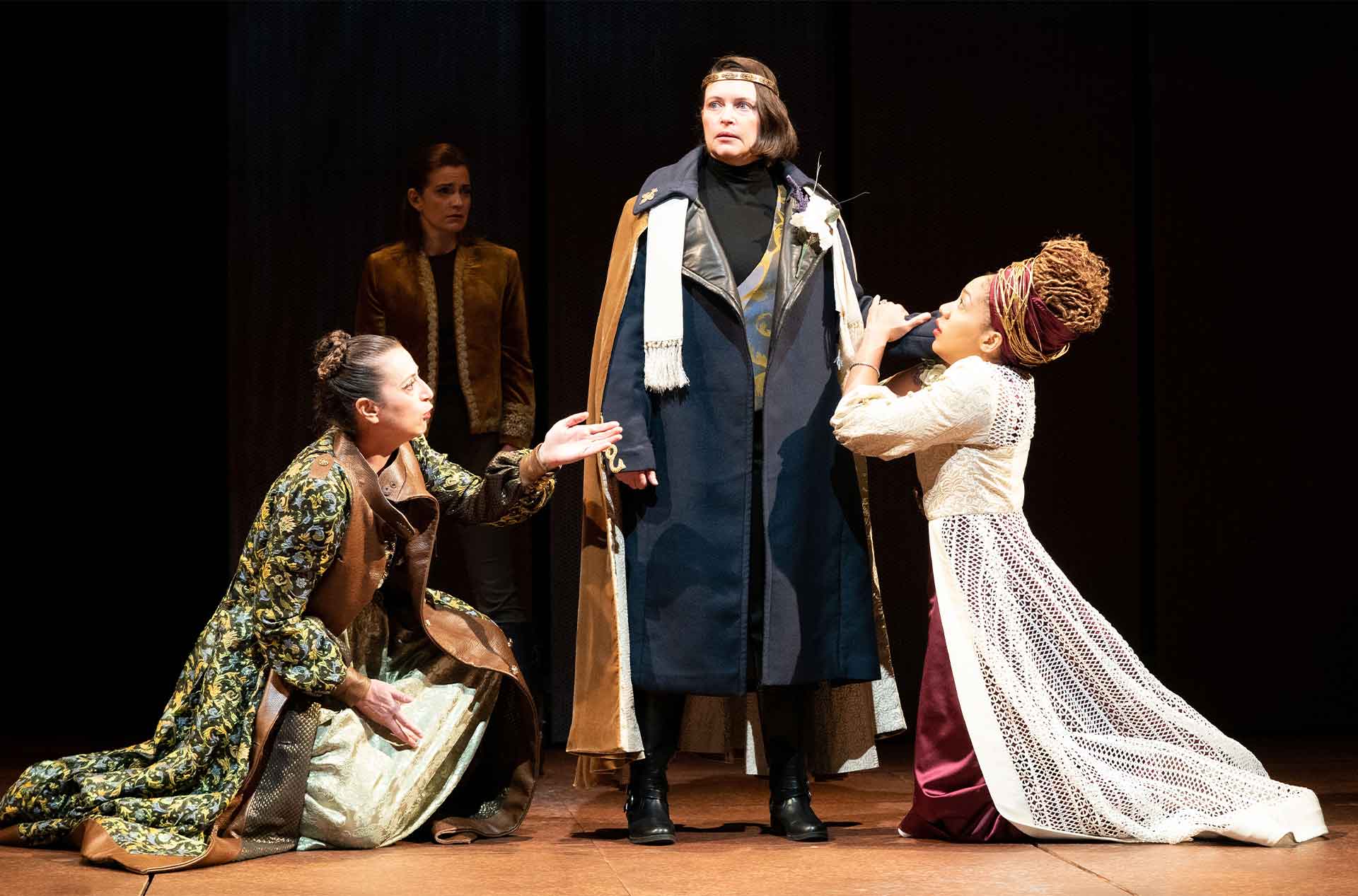 Two people kneeling in front of a someone while another person watches from the background.