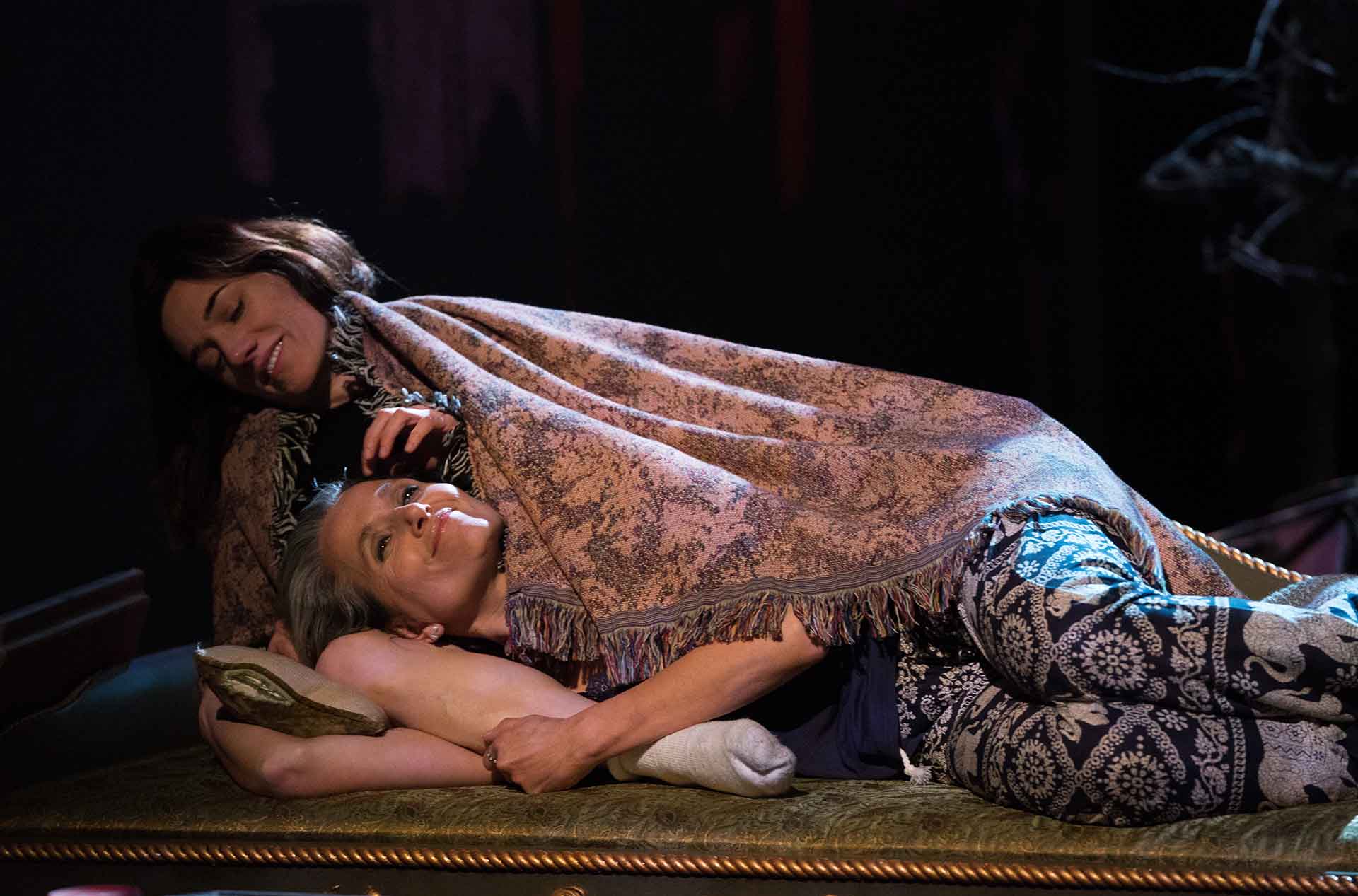 Two people laying on a couch smiling.