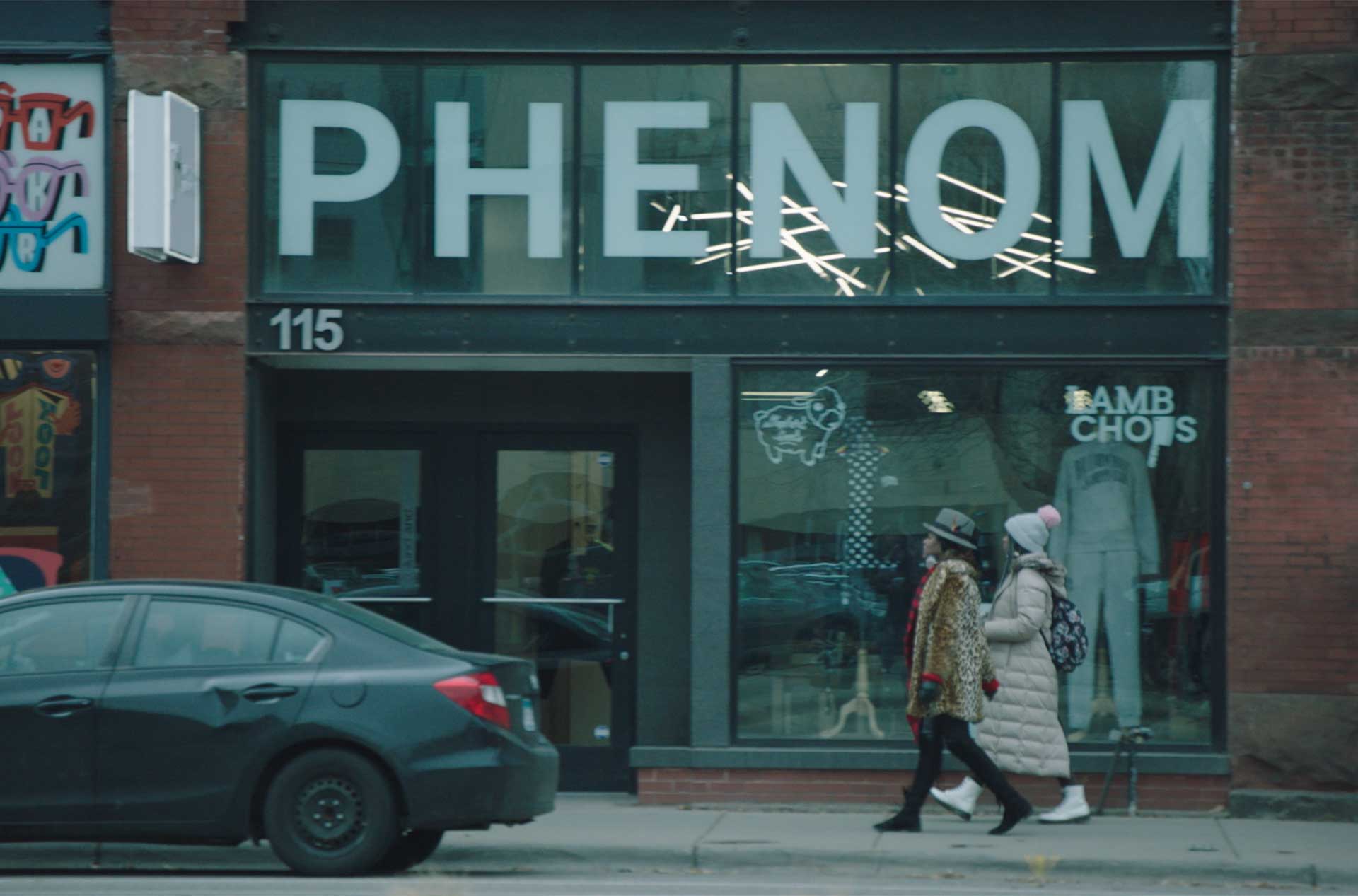 Two people walking past a store.