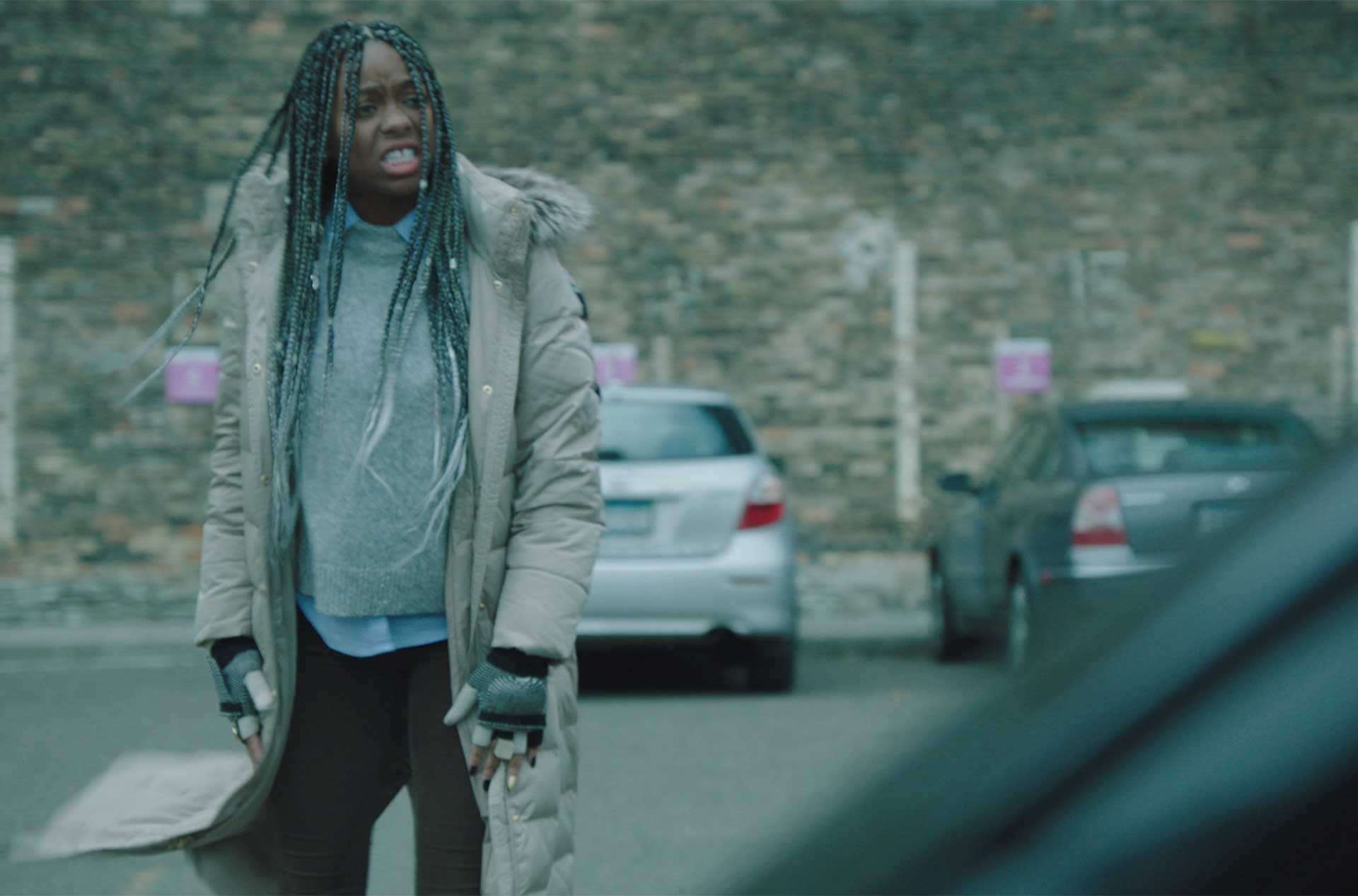 Person standing in a parking lot appearing to be talking to someone in a car.