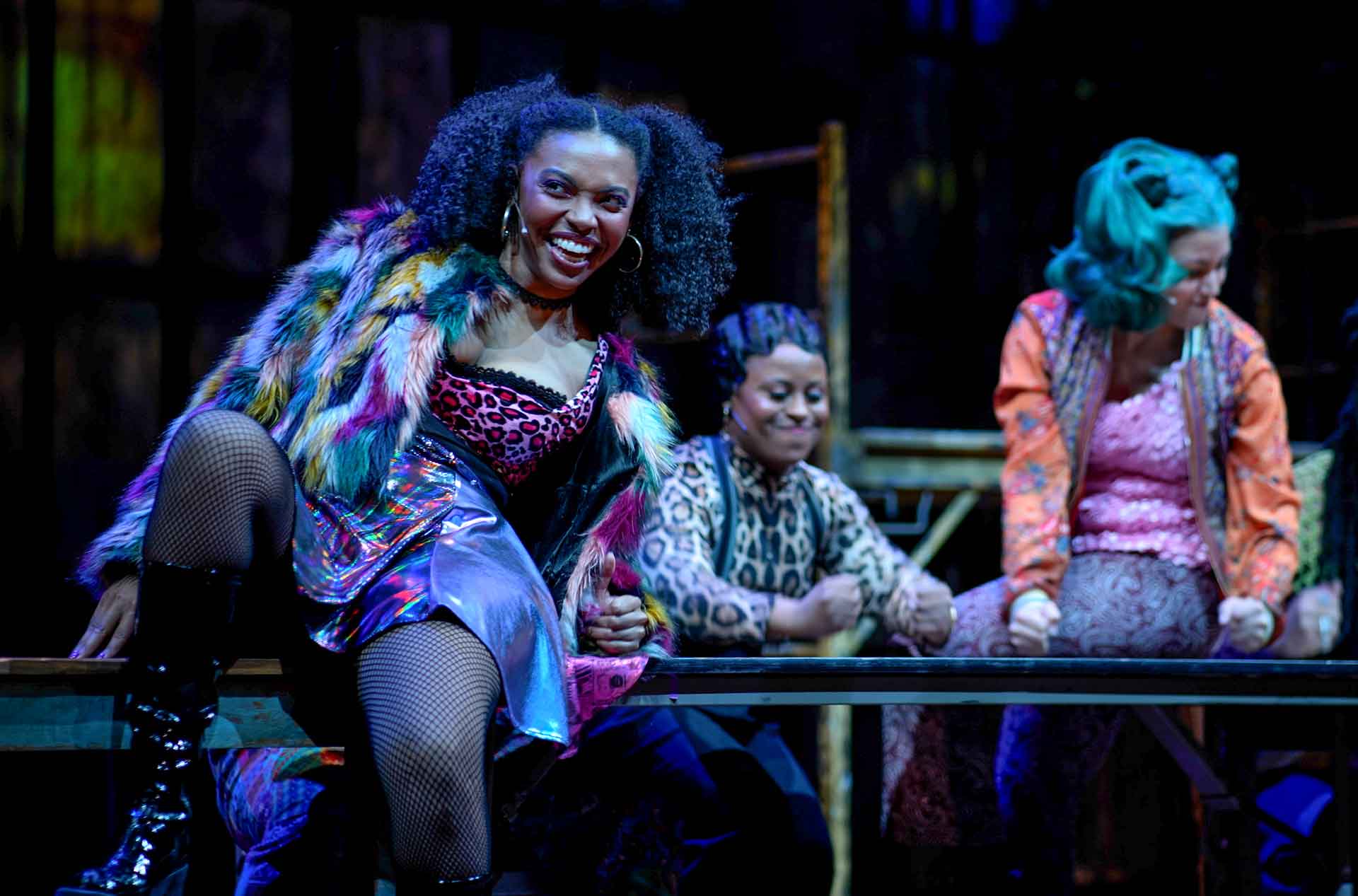 A person sitting on a table smiling with two other people behind the table.