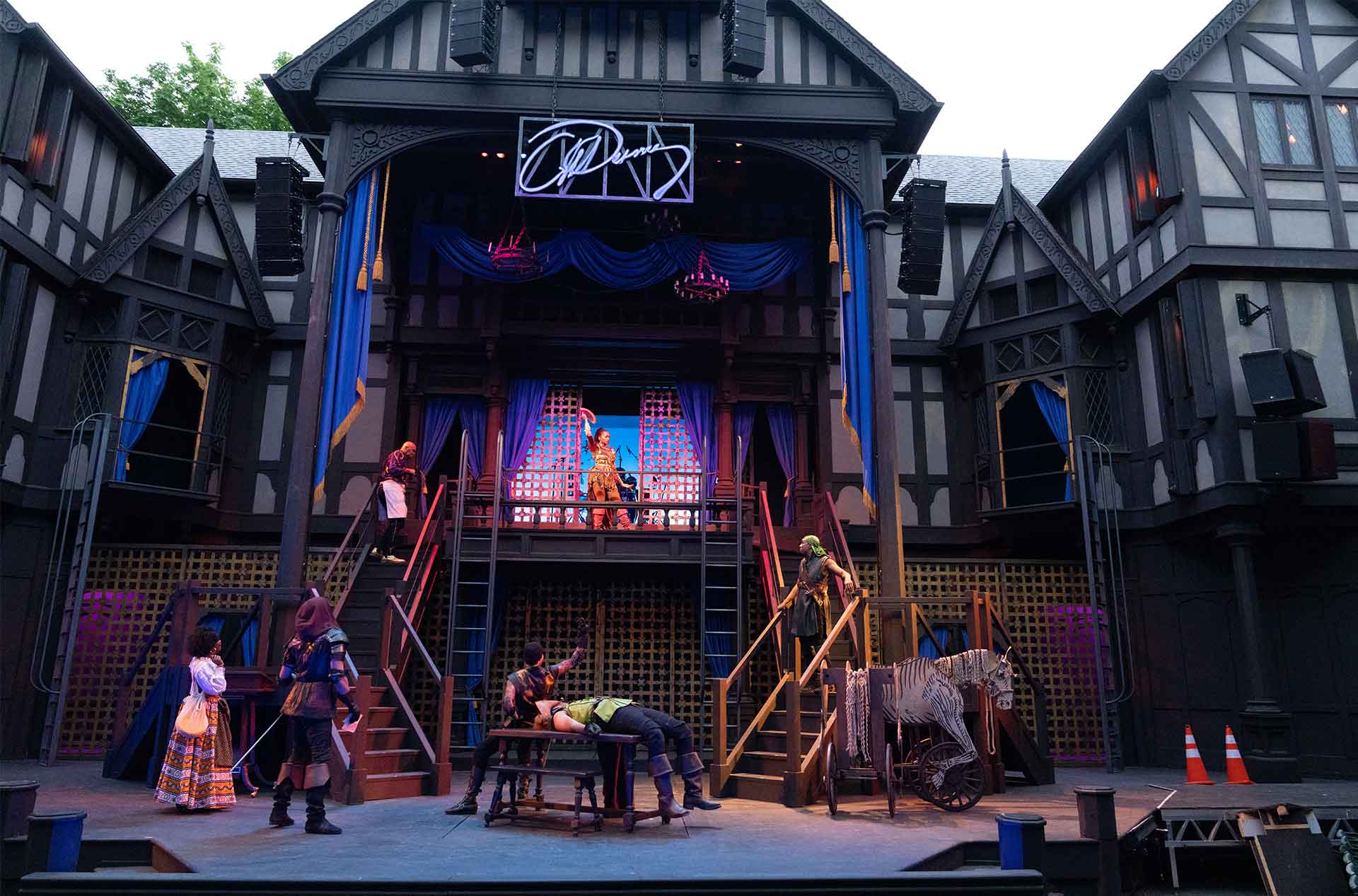 A wide shot the stage with actors looking up at the person on the balcony.