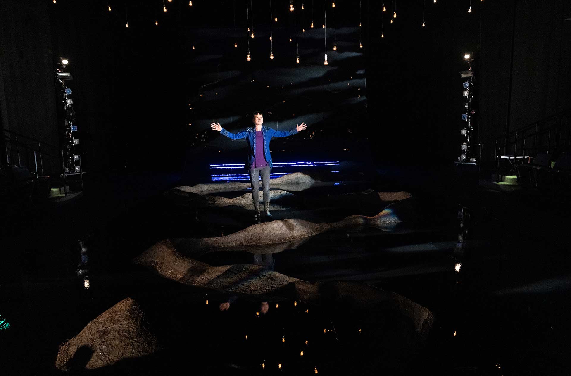 A person standing on the stage looking out toward the audience. 