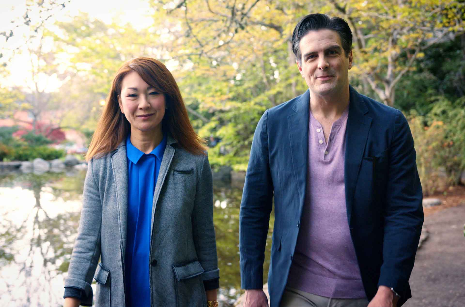 Two people walking by a pond.