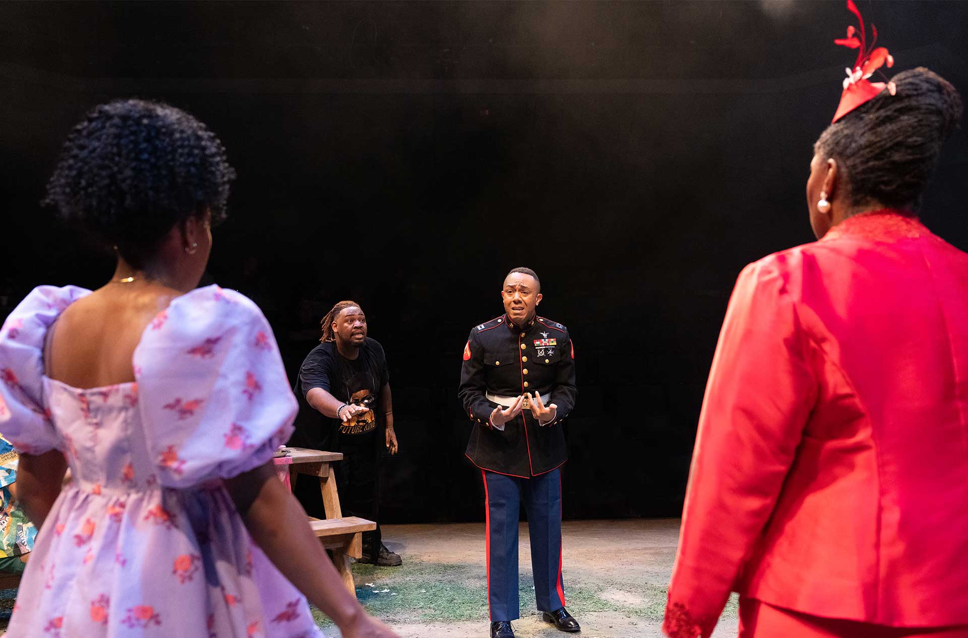 A person in a military uniform speaks emotionally to others surrounding them in a tense theatrical moment.