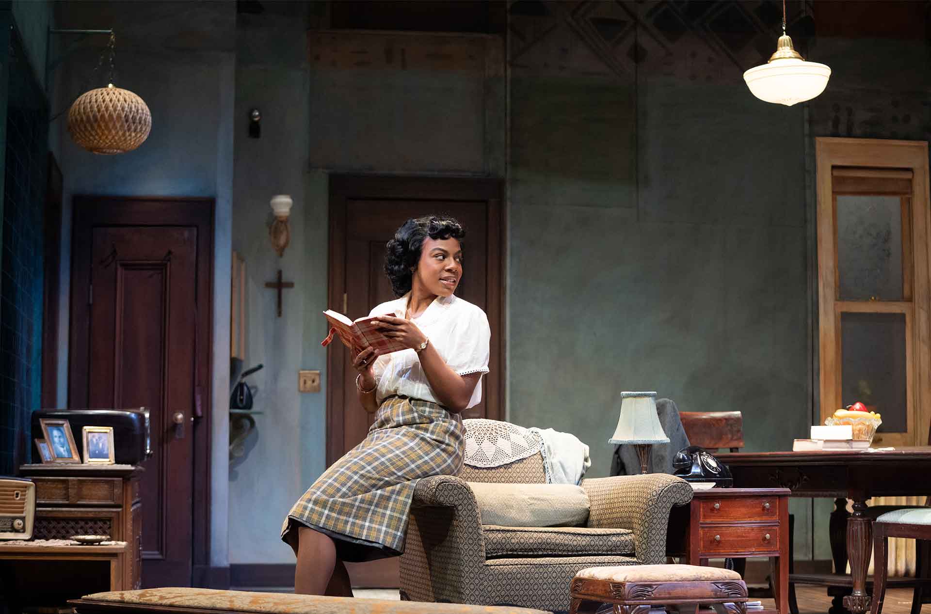 One person sits on a chair reading a book in a warmly lit living room with vintage decor.