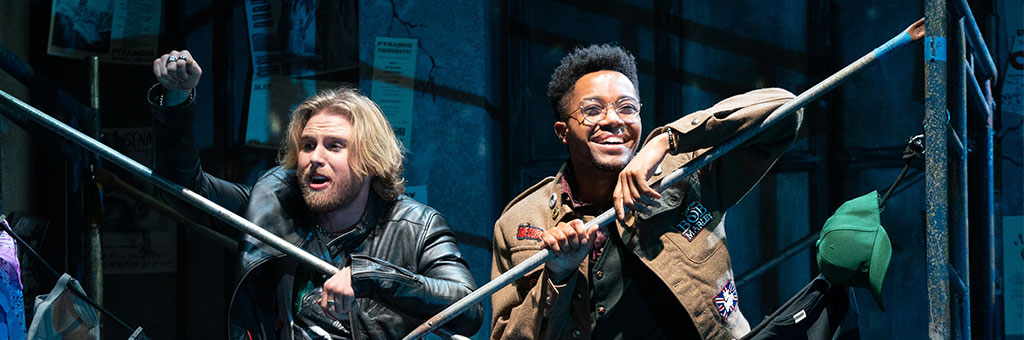 Two people leaning on scaffolding smiling.
