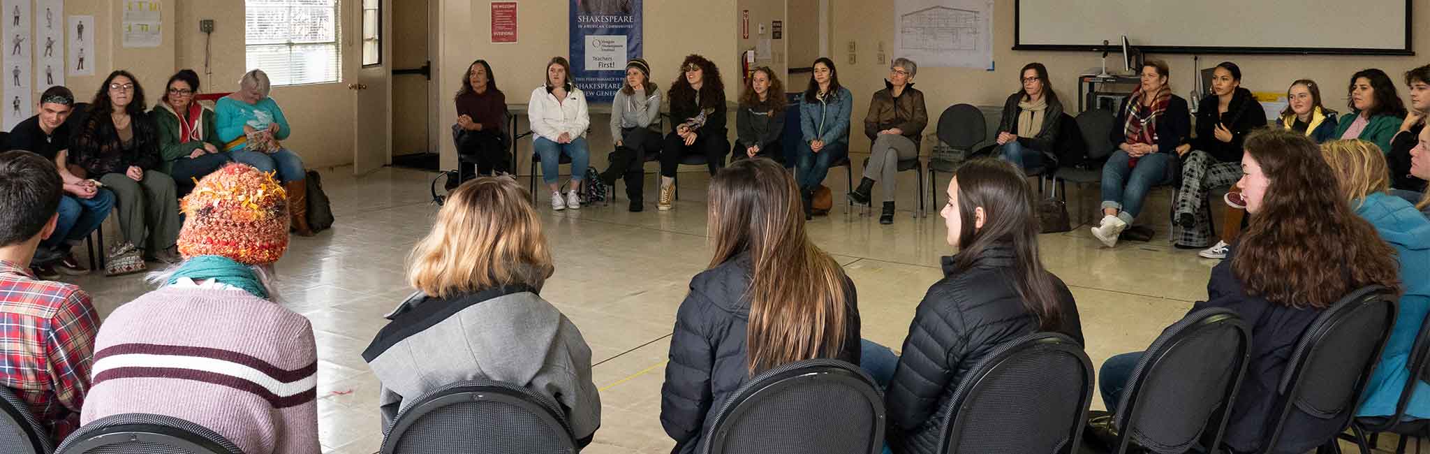 Group of people sitting in a large circle having a discussion.