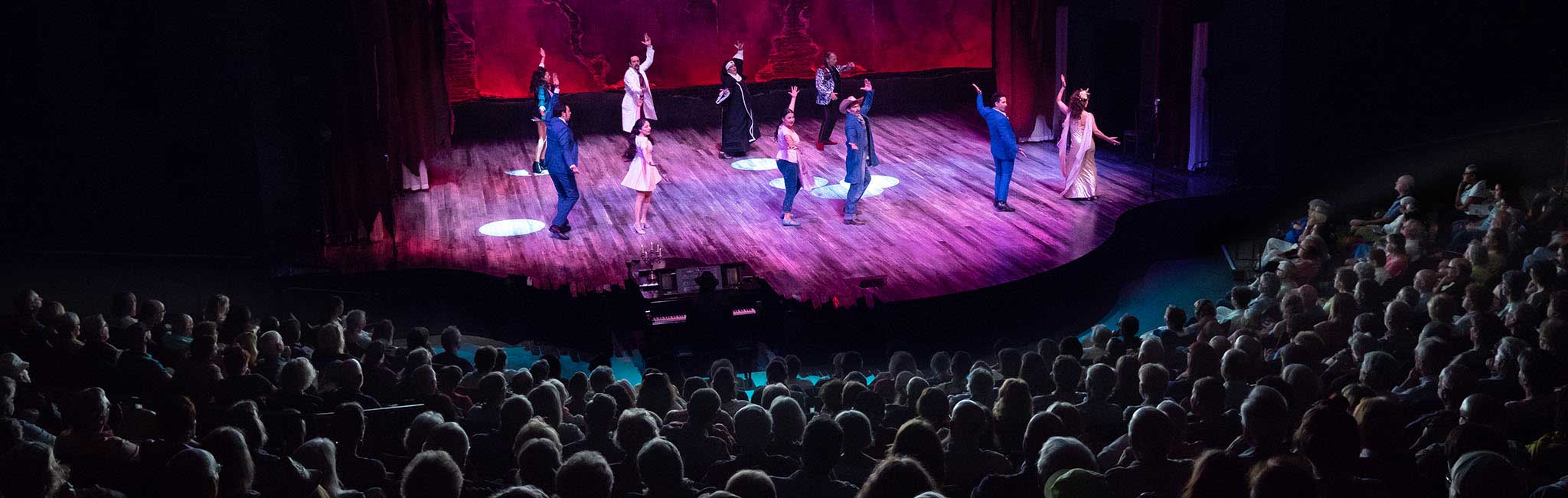 People dancing on the Angus Bowmer stage with the audience in the foreground.