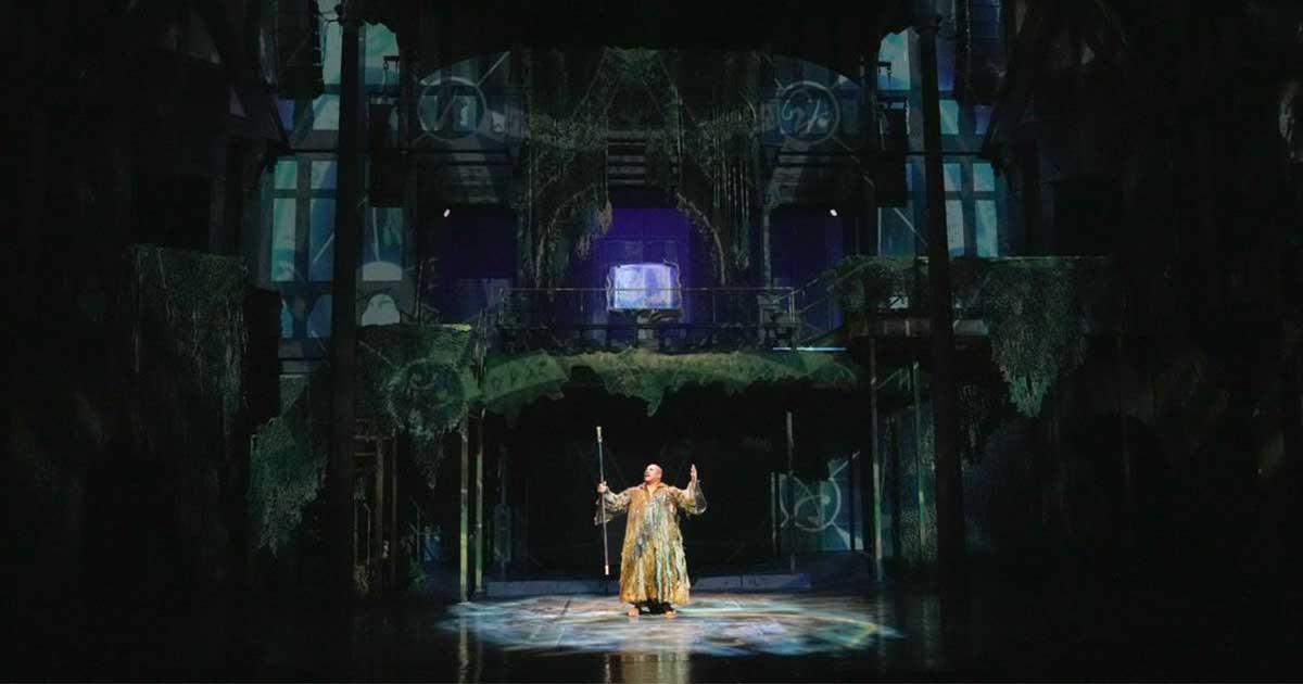 Man holding a staff reaching up the sky with both hands.